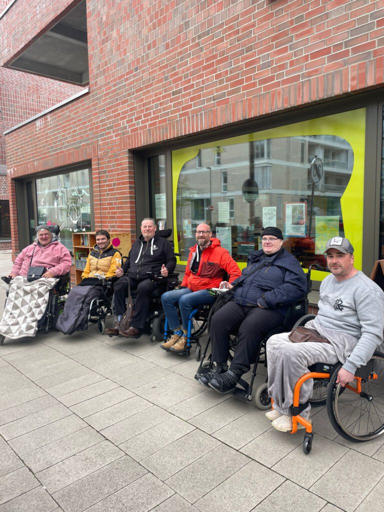 Sechs Männer im Rollstuhl vor dem Büro von Jetzt Hier Quartiersentwicklung