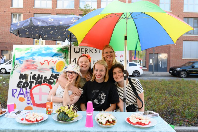 Fünf Frauen an einem bunten Picknick Tisch mit Melonen, Käse und Trauben Spießen. 