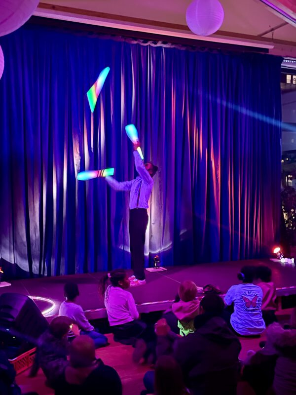 Ein Lichtkünstler jongliert mit leuchtenden Kegeln.