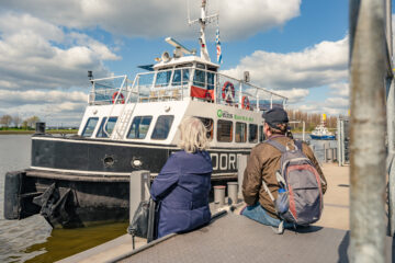 Das ist der Schiffsanleger Pier 2 / Waterfont. Zwei Personen und ein Hund sehen wie die Weserfähre Bremen am Anleger anlegt