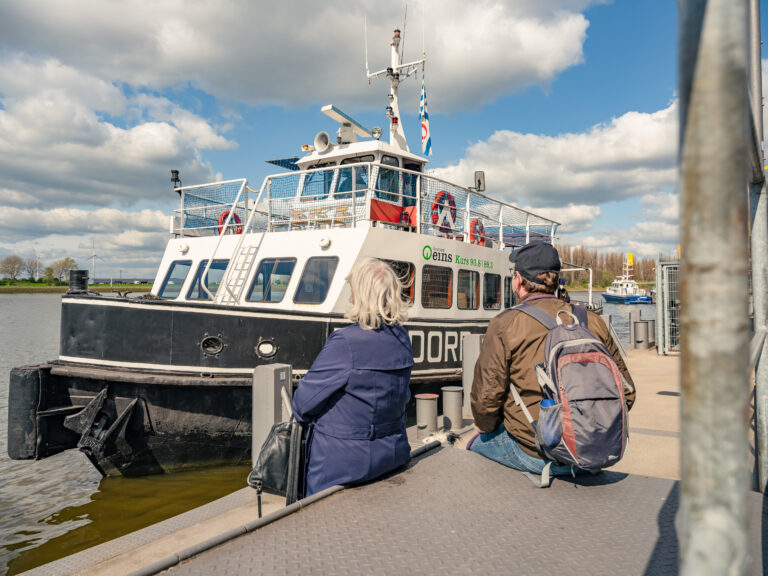 Das ist der Schiffsanleger Pier 2 / Waterfont. Zwei Personen und ein Hund sehen wie die Weserfähre Bremen am Anleger anlegt